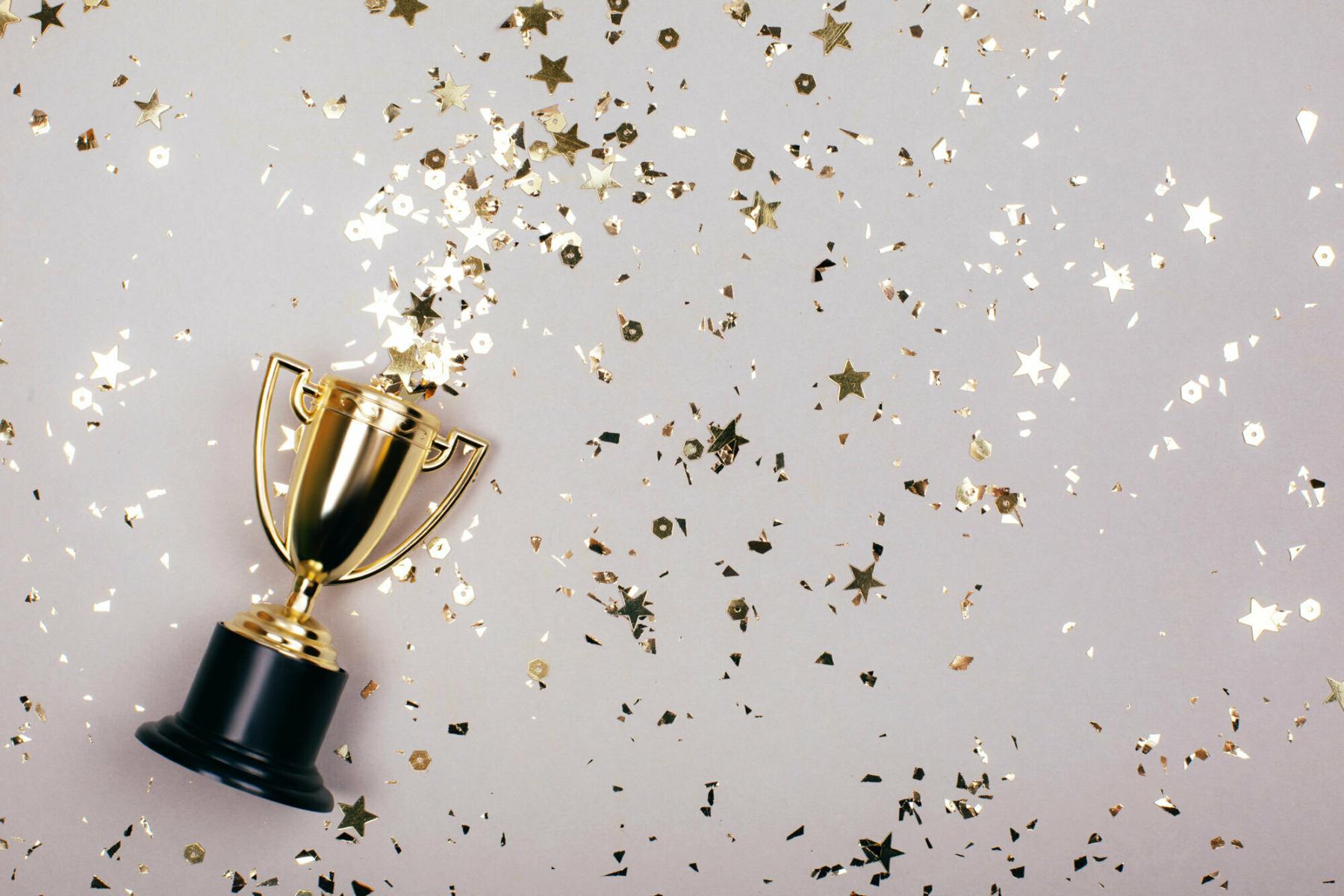 trophy on beige background with gold confetti